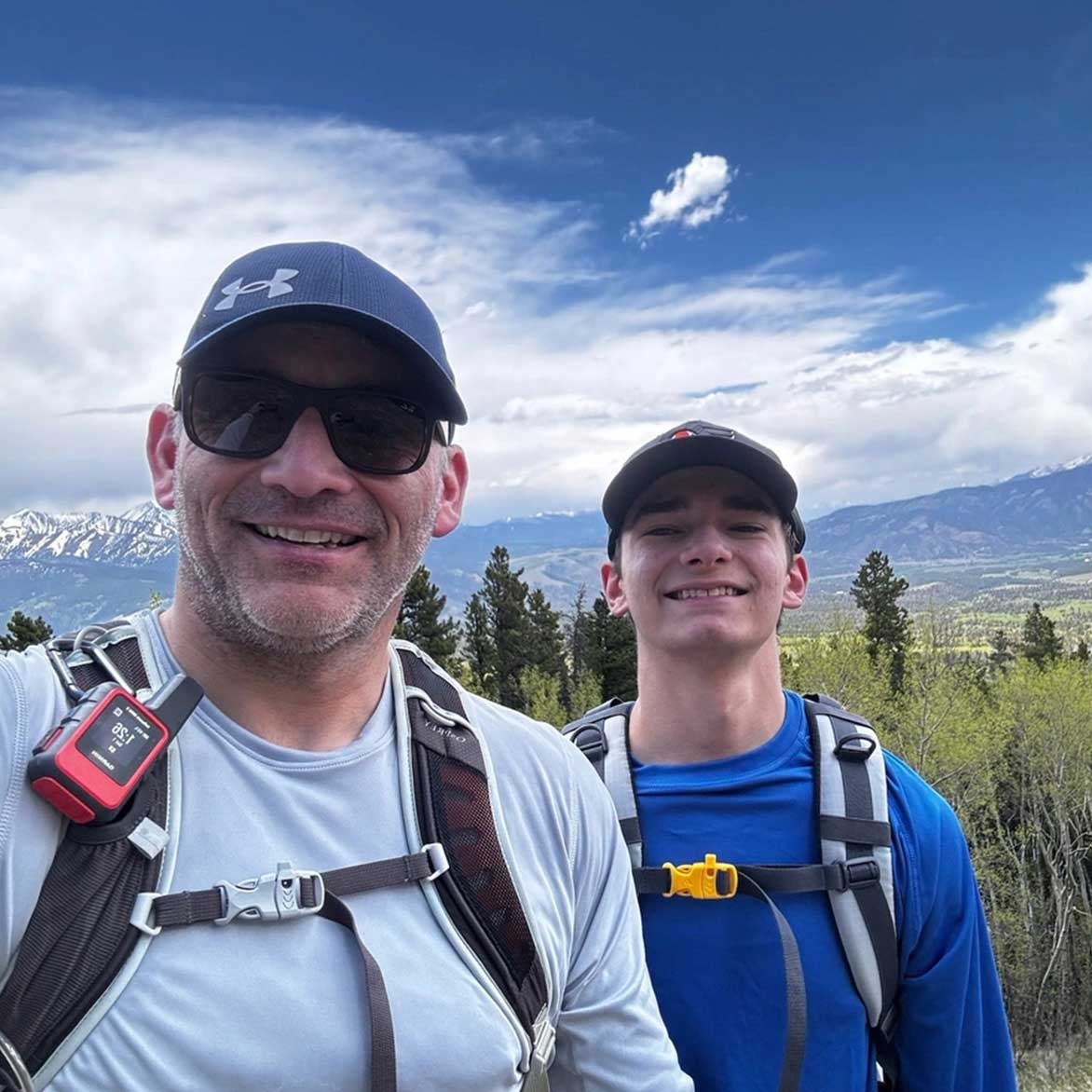 Mark O'Donnell and young man standing on a hill while hiking