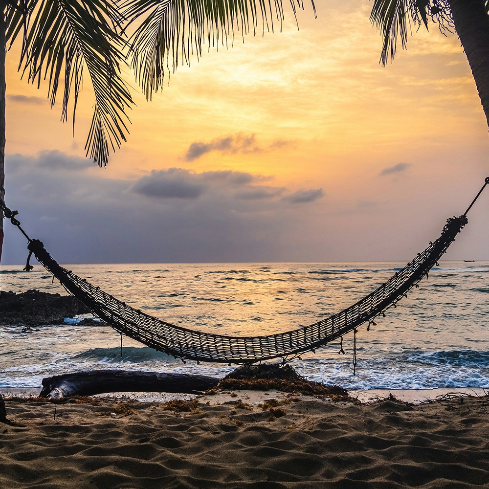 A hammock sways in the breeze on the beach.