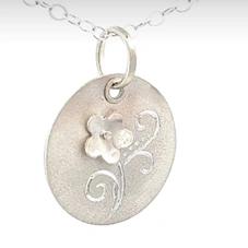 Silver circle pendant with a 3d flower and swirly engraved leaves