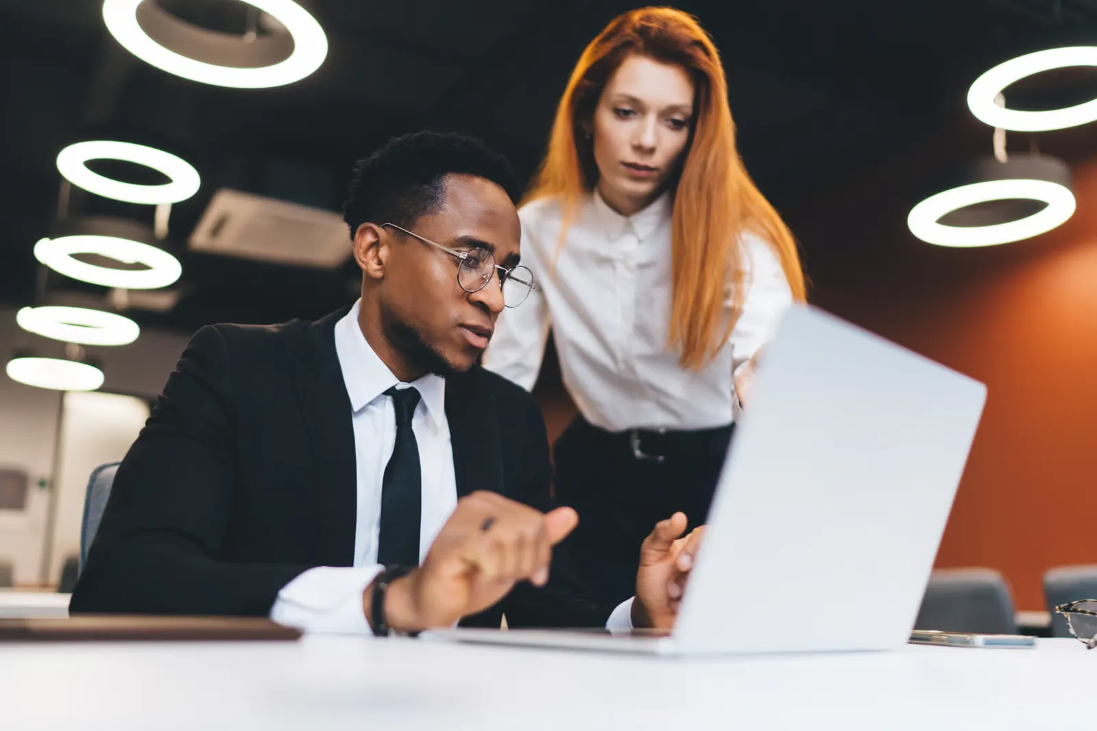 Two professionals discussing information while working on a laptop