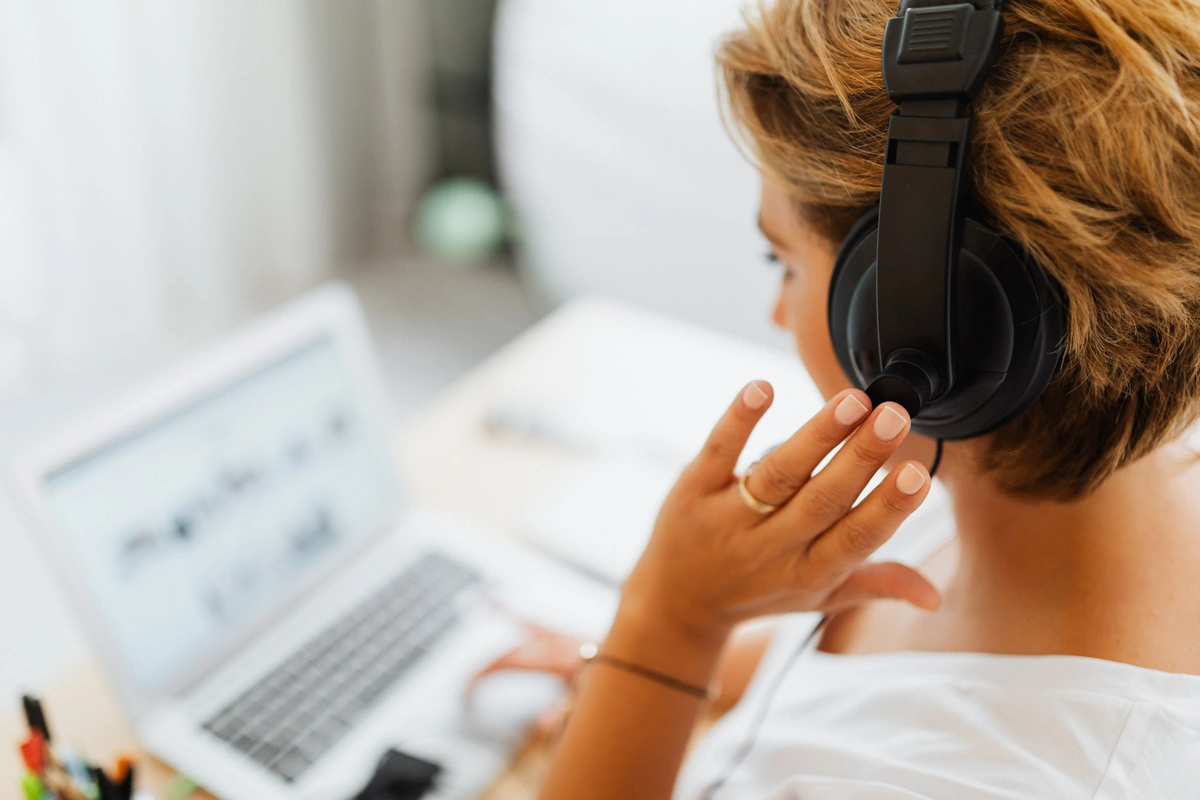 Woman wearing headphones in front of laptop as she reads a sales script