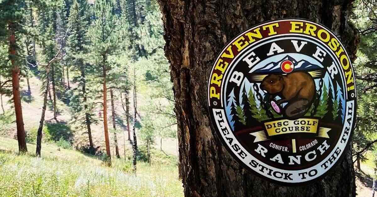 A sign on a tree asking disc golfers to stay on paths to help fight erosion
