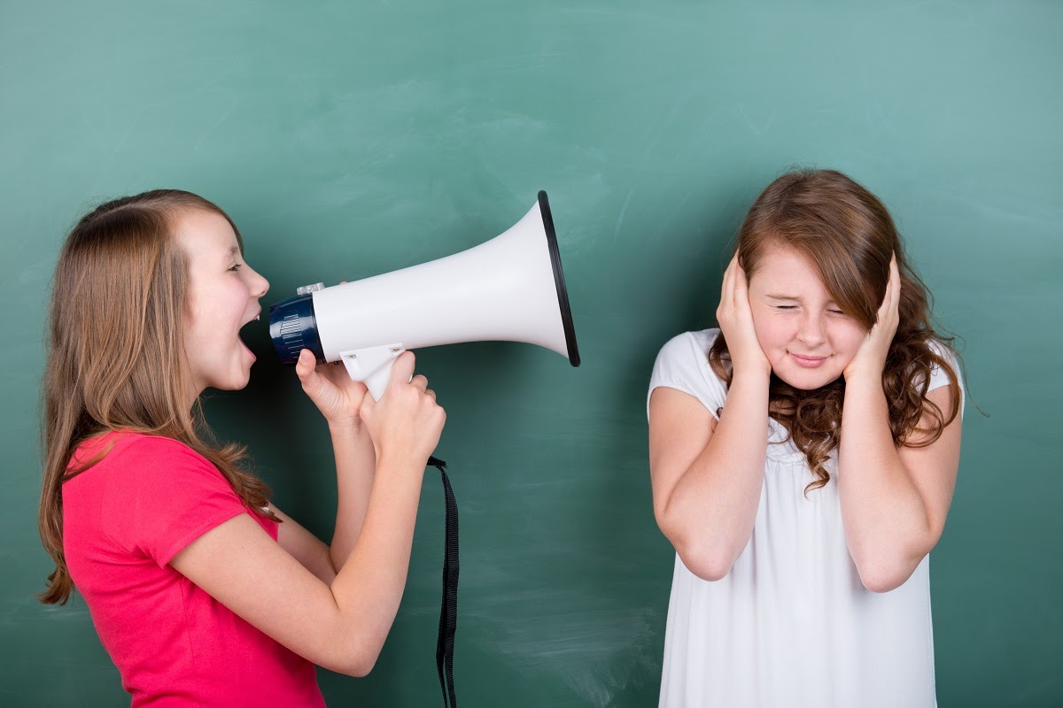 Hearing test results: A young girl speaks into a megaphone while another girl covers her ears