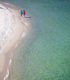 Couple walking along the shoreline at an Alabama beach
