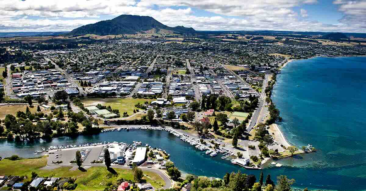 An aerial view of a city near a lake with a river running to it and a mountain in the distance