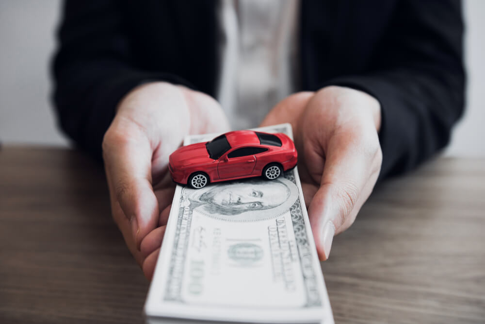 hands holding toy car on stack of tennessee car title loan cash