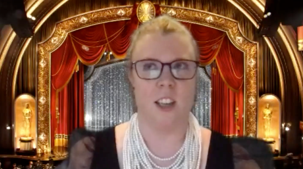 Woman on Zoom Call with dress and necklces and movie theater backdrop