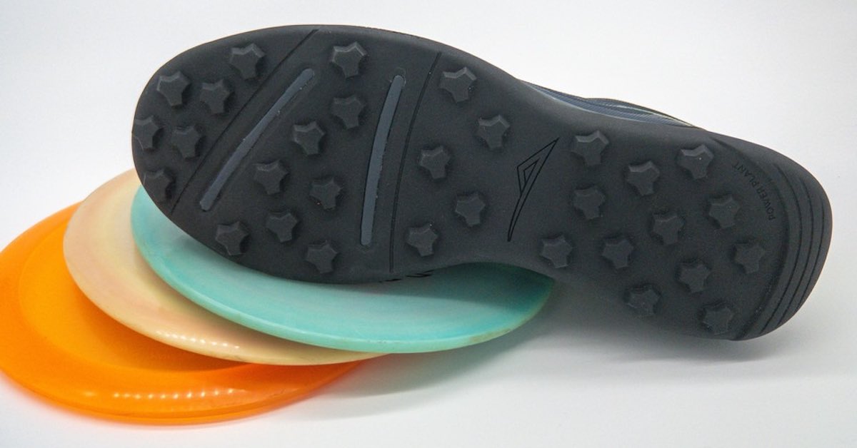 A shoe with sole facing camera on top of disc golf discs
