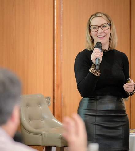 Strategic Coach Team Member holding a microphone and speaking to entrepreneurs in a workshop