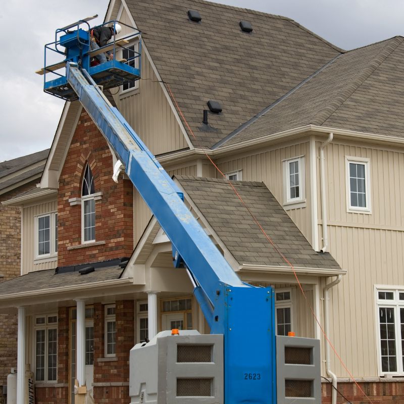 Blue telescopic boom lift working on windows in a residential home