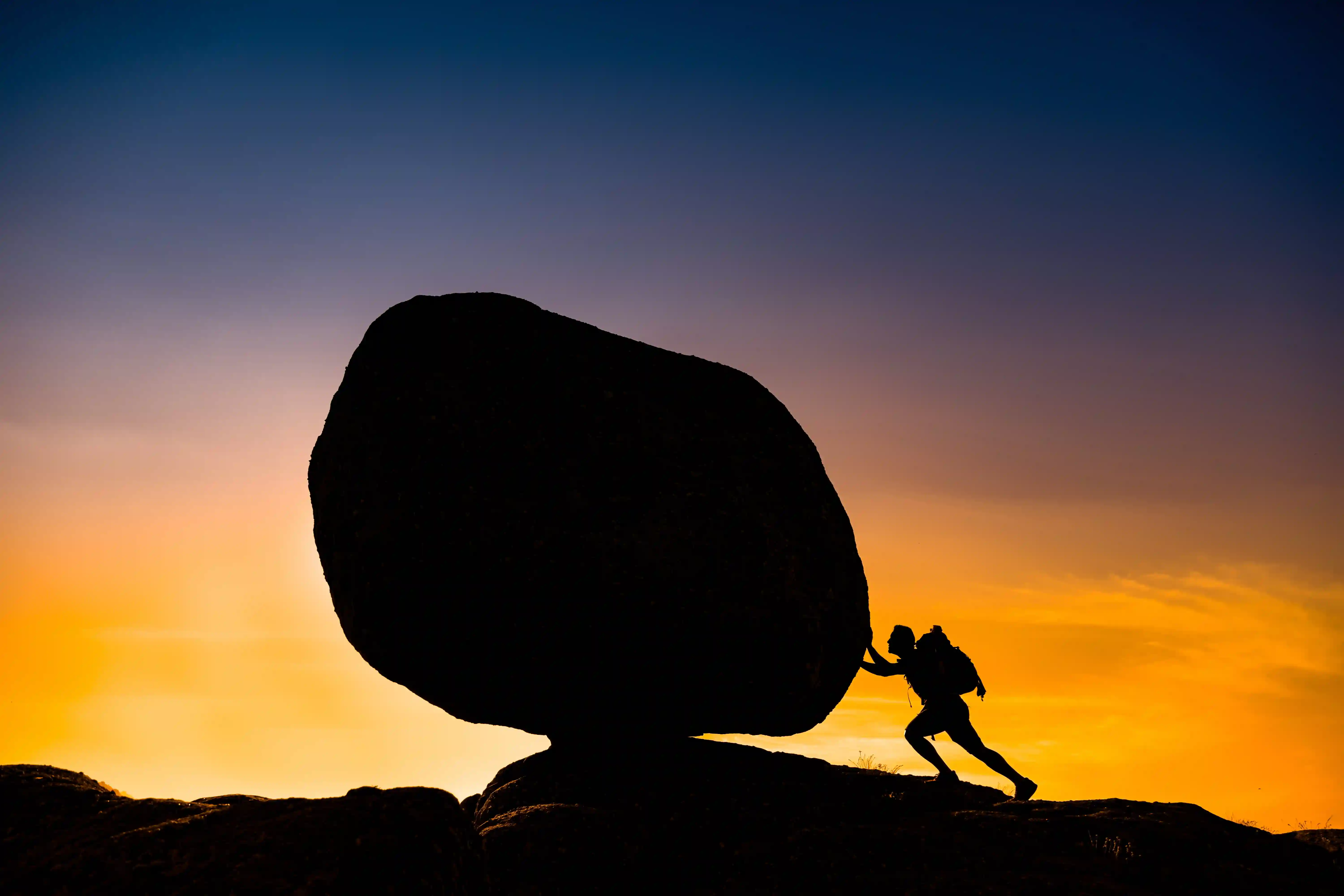 Person pushing large rock uphill symbolizing operational burden and inefficiency in business