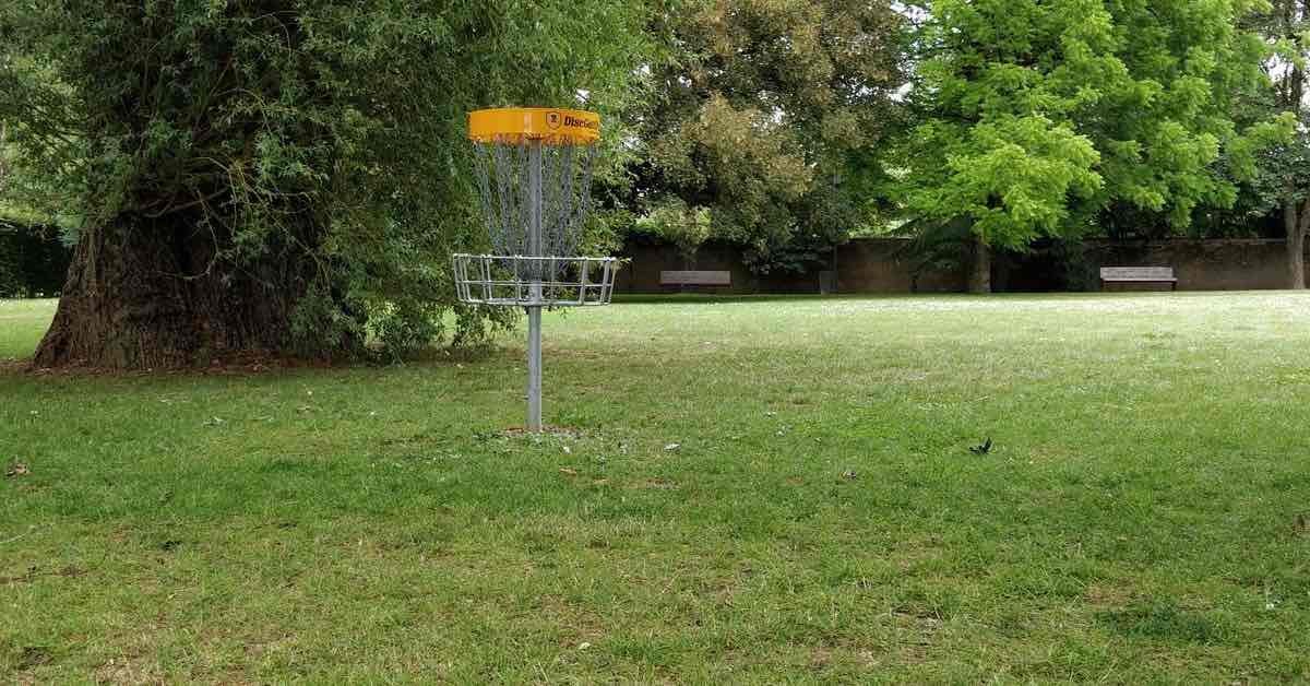 A yellow-banded disc golf basket in a park