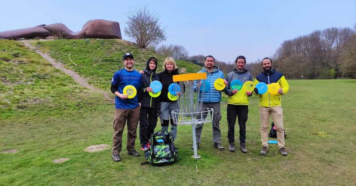 A group poses next to a disc golf basket with discs in Ukrainian flag colors