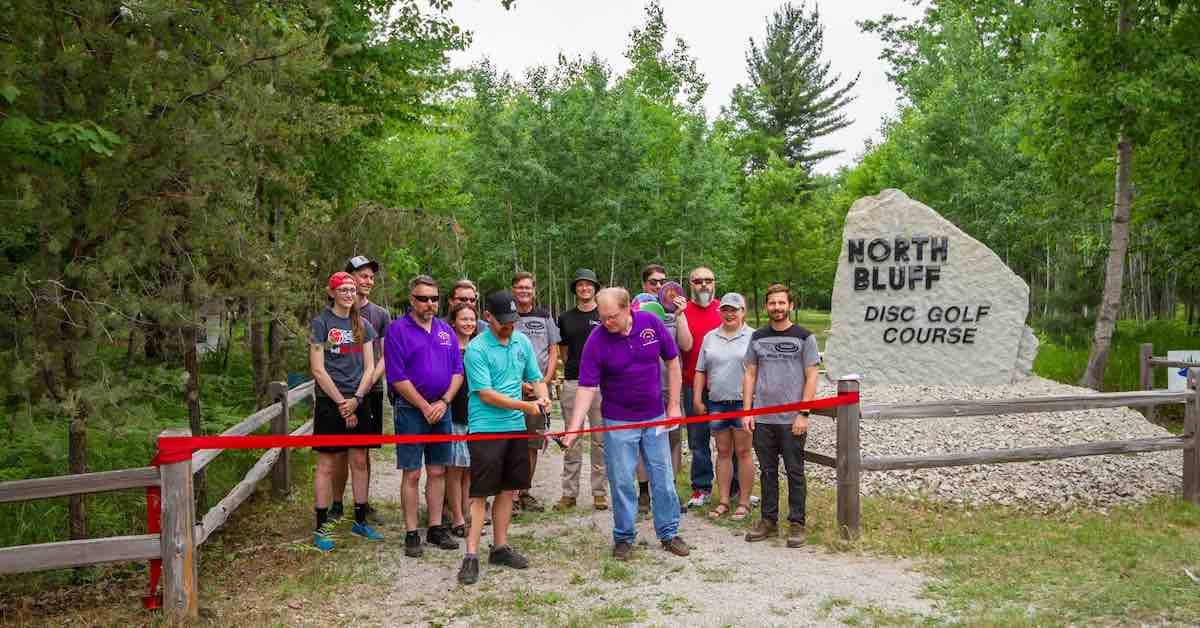 People at a ribbon cutting ceremony for a disc golf course