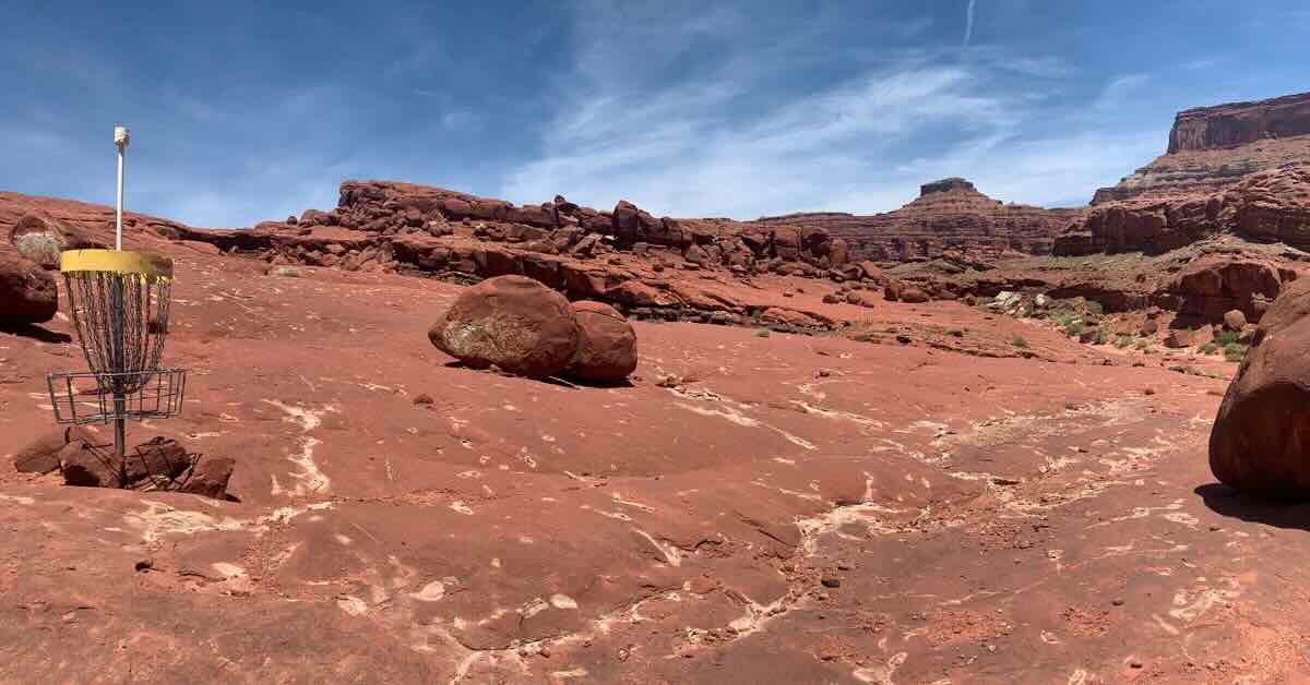 A disc golf basket in a vast area of red rock desert