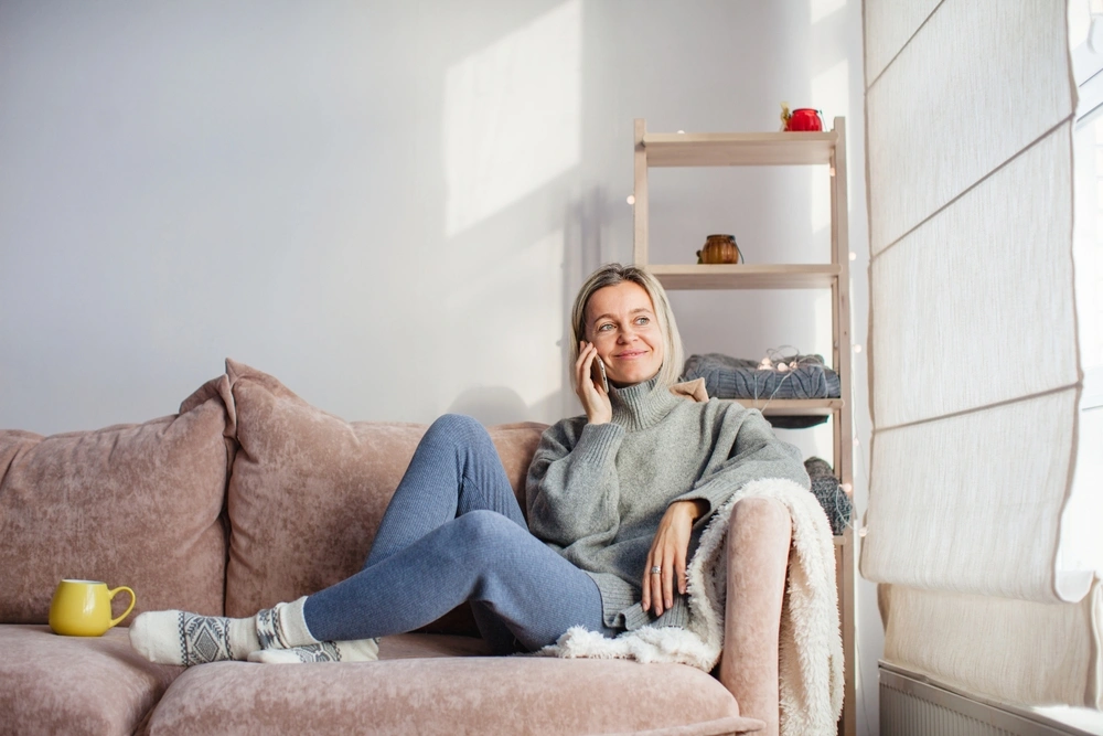 relaxed woman sitting on the sofa on her mobile phone