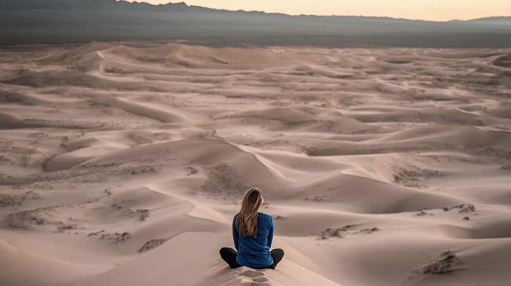 Woman meditating on sand dune
