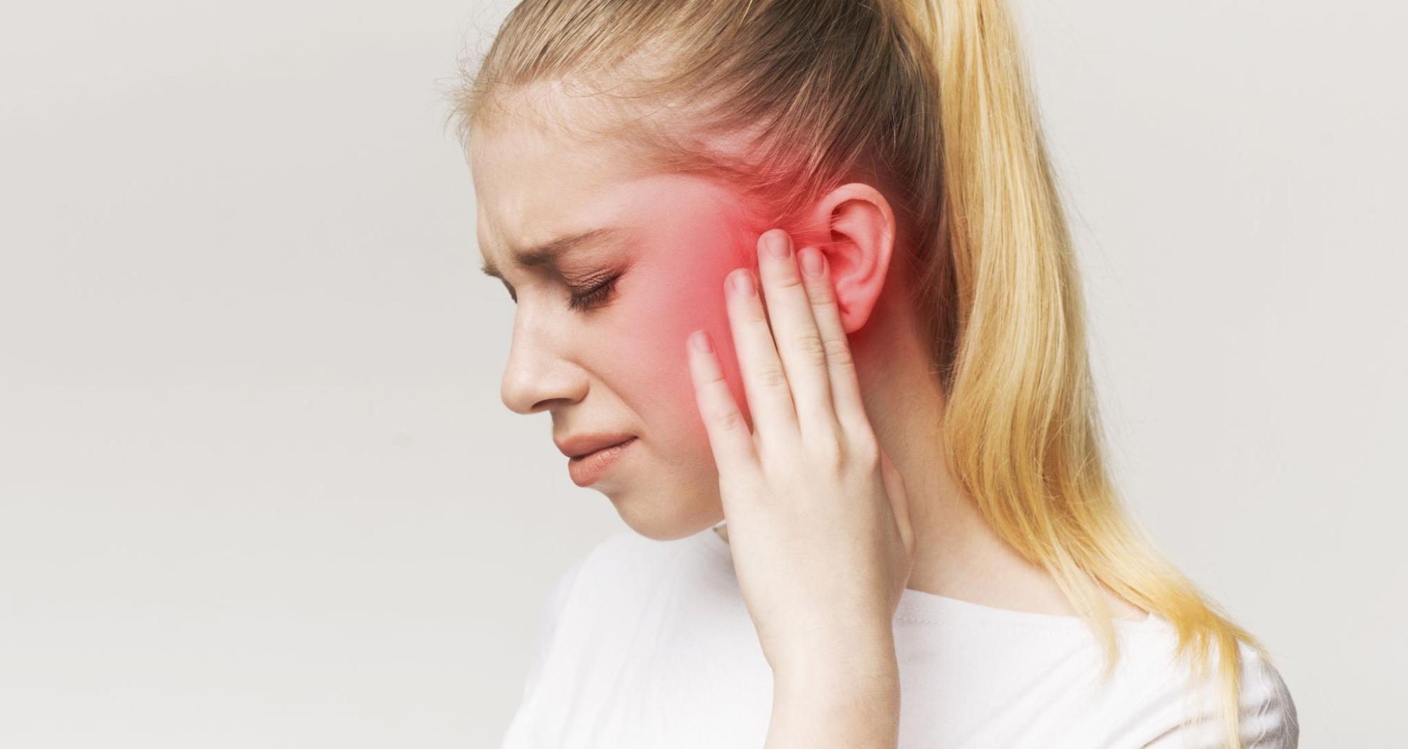 ear irrigation: Woman holding up a hand to her ear in pain