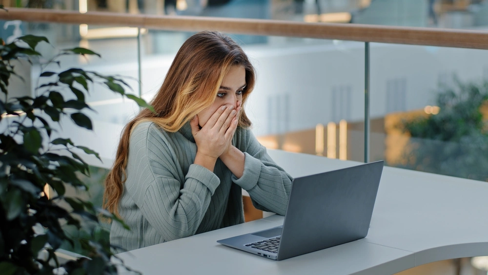 woman looking shocked on laptop