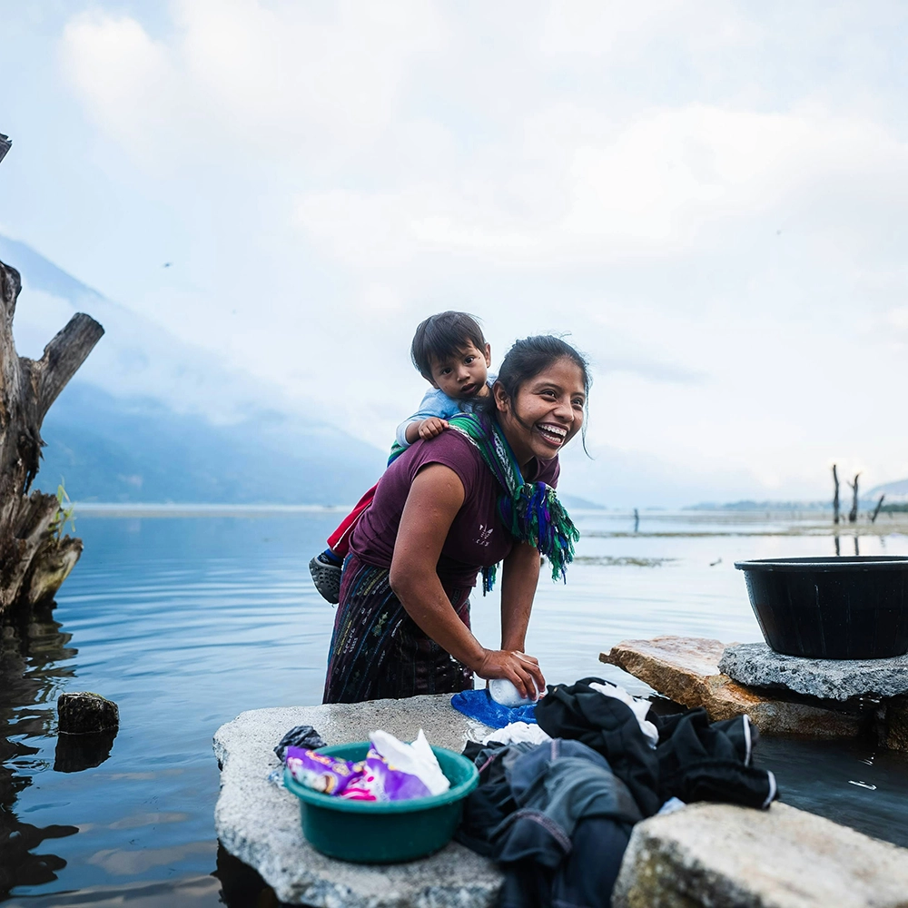 Woman doing laundry in the fresh water.webp