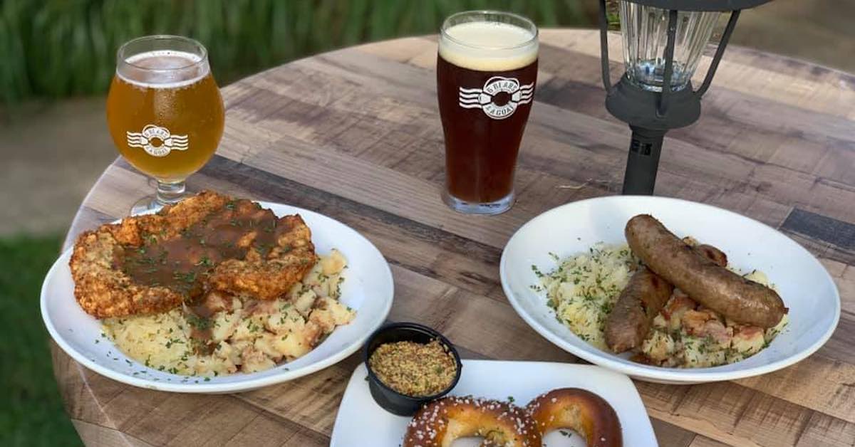 Two beers and plates of German food on an outdoor table