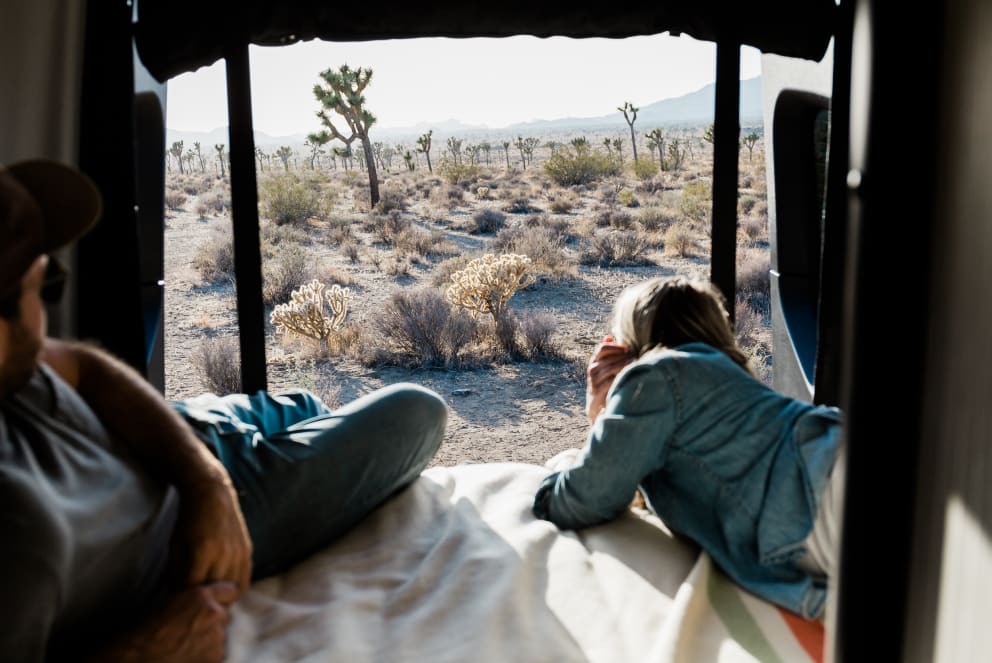 man and woman sitting inside winnebago revel in joshua tree california