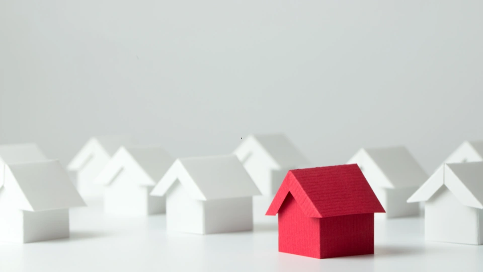 A red house standing out among a row of white homes