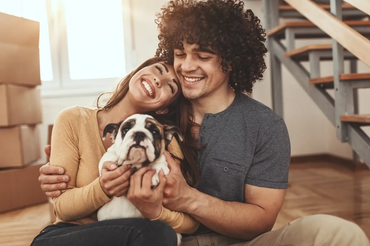 A couple snuggles with a puppy in their new living room