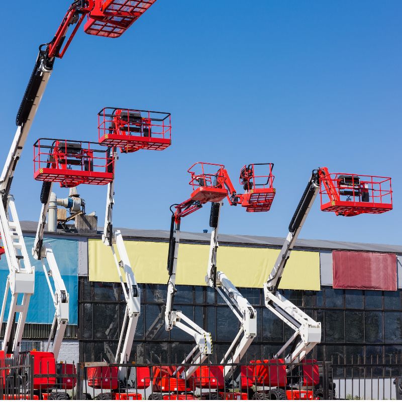White and orange articulating boom lifts of different heights in a supplier yard