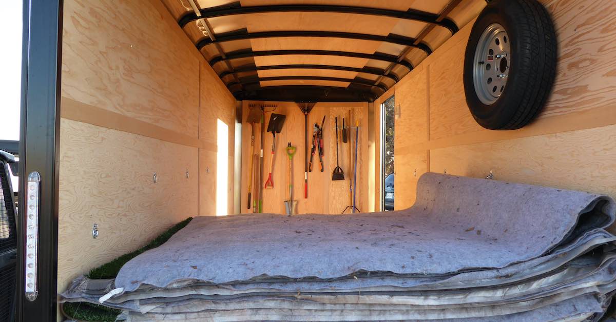 Turf tee mats stacked in a trailer with wooden paneling inside