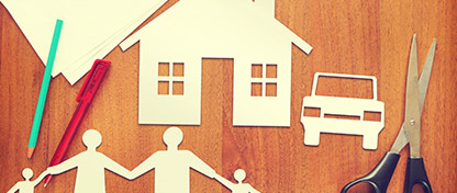 Paper cut out of a family holding hands and a house with a car