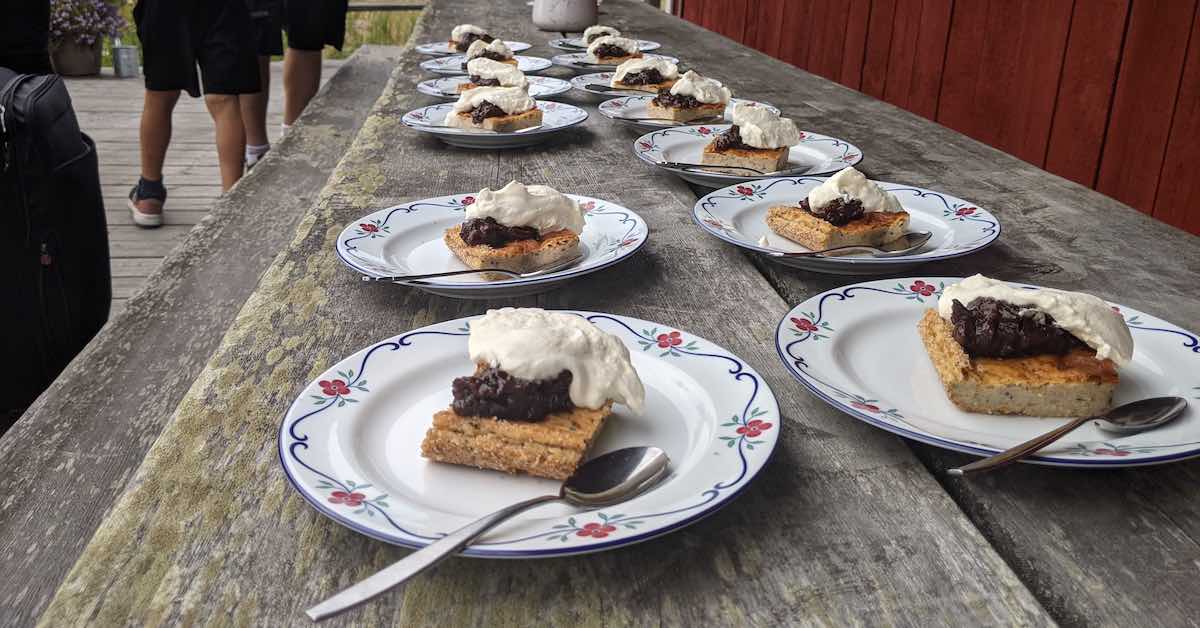 Cakes with jam and whipped cream lined up on an old picnic table