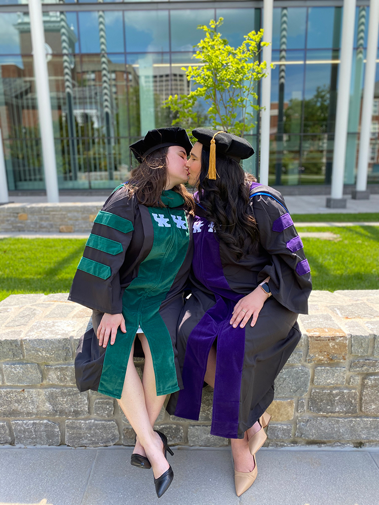 two women kissing at graduation