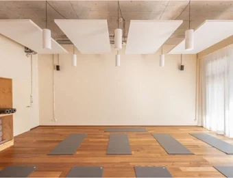 Yoga-Studio mit klarer Sicht zur Lehrperson im vorderen Bereich des Raumes, offene Raumgestaltung mit ausreichend Platz für Teilnehmende während der Yoga-Stunde.