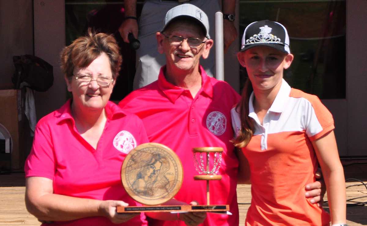 An older woman, older man, and young woman stand together posing for a photo at an awards ceremony