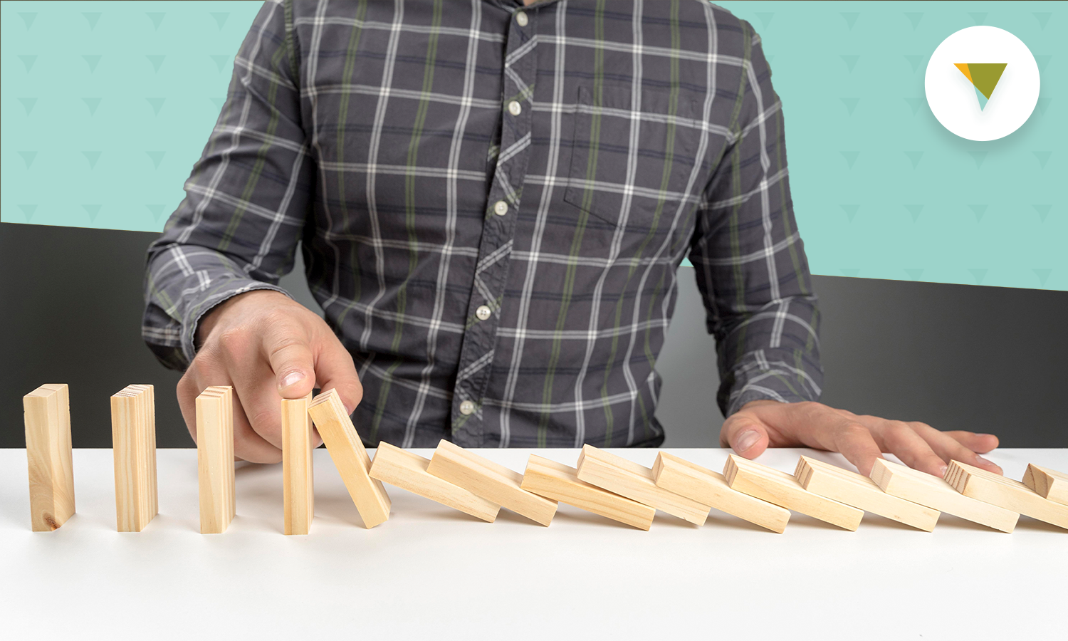 Man knocking dominoes down on table.