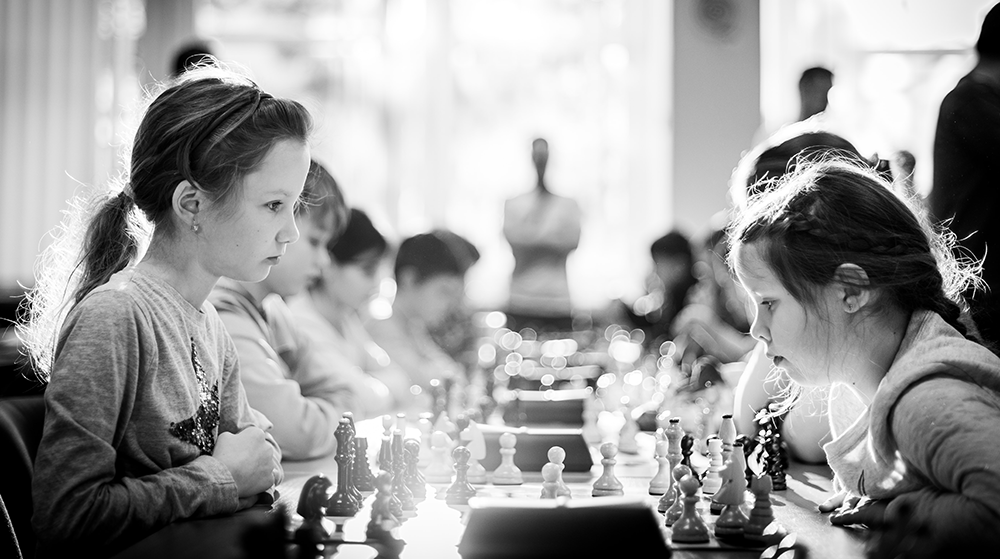 Two young girls playing chess at a tournament