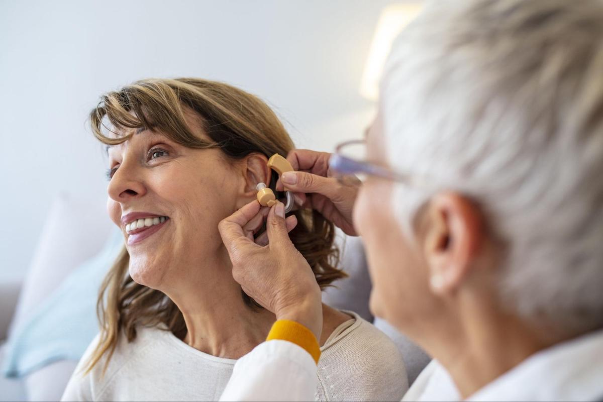 EPIC Hearing: Doctor putting a hearing aid on a female patient's ear