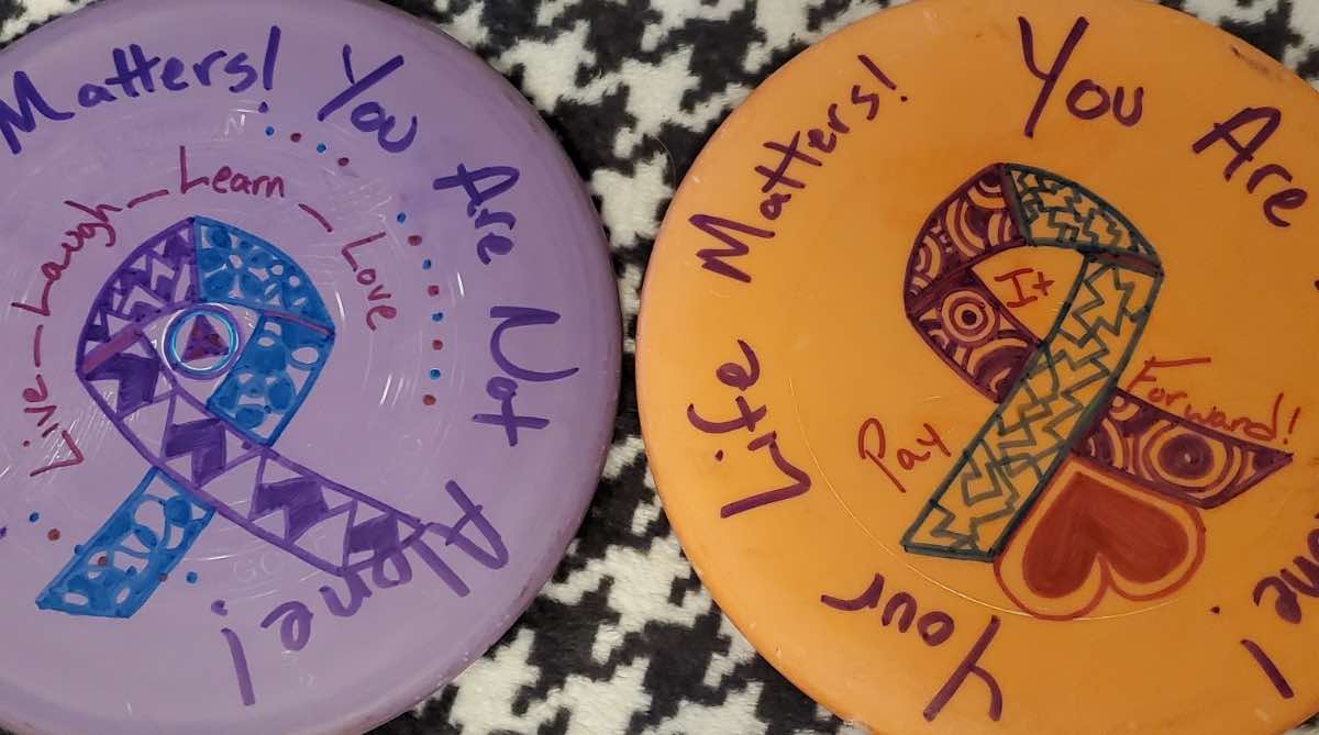 A purple disc and an orange disc with positive messages and drawings