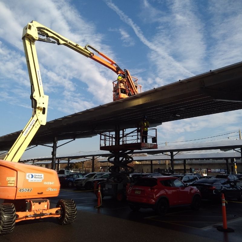 An articulating boom lift doing work on a parking lot structure overhang