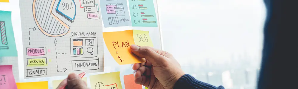 person placing sticky notes on board