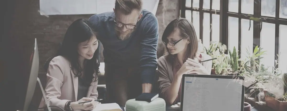 A group of people looking at information on a desk.