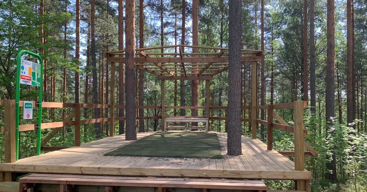A large wooden structure supports a turf disc golf tee pad