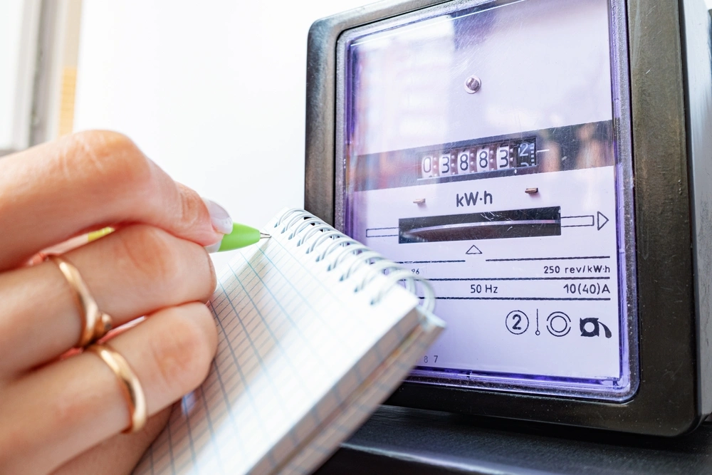 Close up of energy meter with a woman writing on a note pad