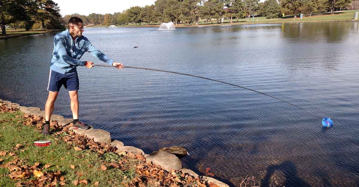 Man using a Kwik-Stik disc golf disc retriever to fetch a disc from a lake