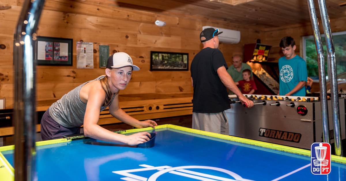 A young woman in a white hat is very seriously playing air hockey