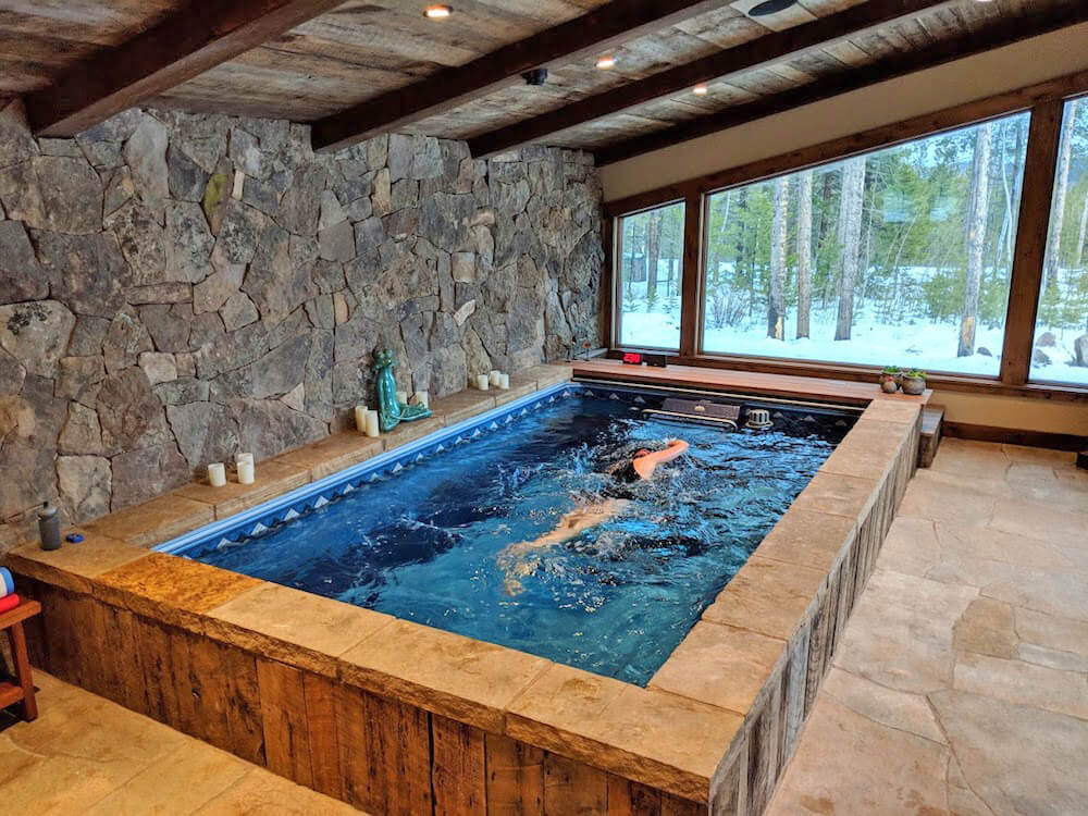 A triathlete swimming in a Performance Endless Pool in a sunroom.