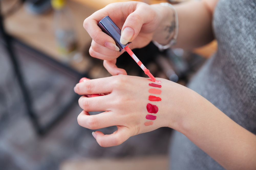 woman testing lip-gloss samples on the back of her hand