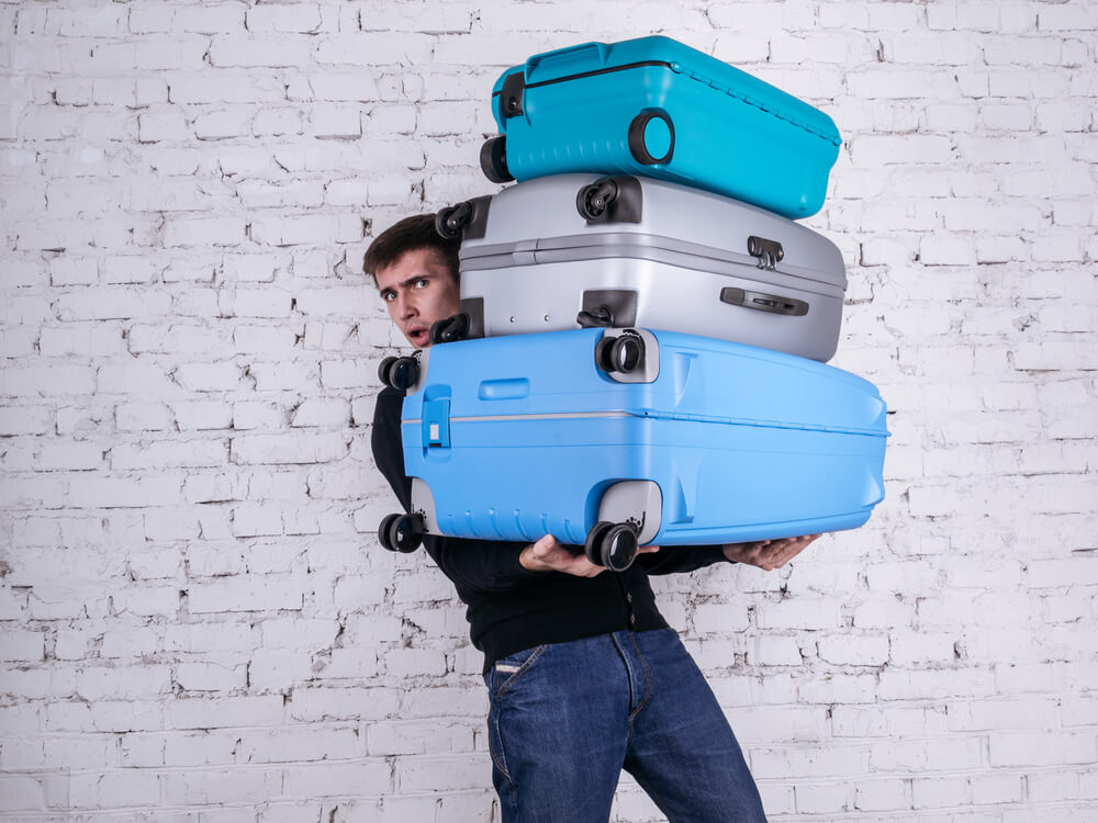 man carrying too much luggage