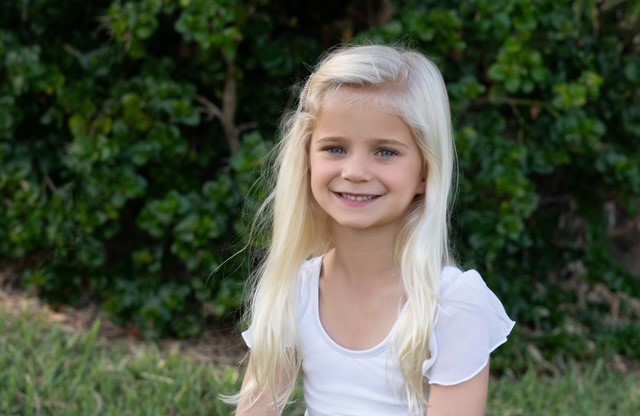 A child with long blonde hairDescription automatically generated